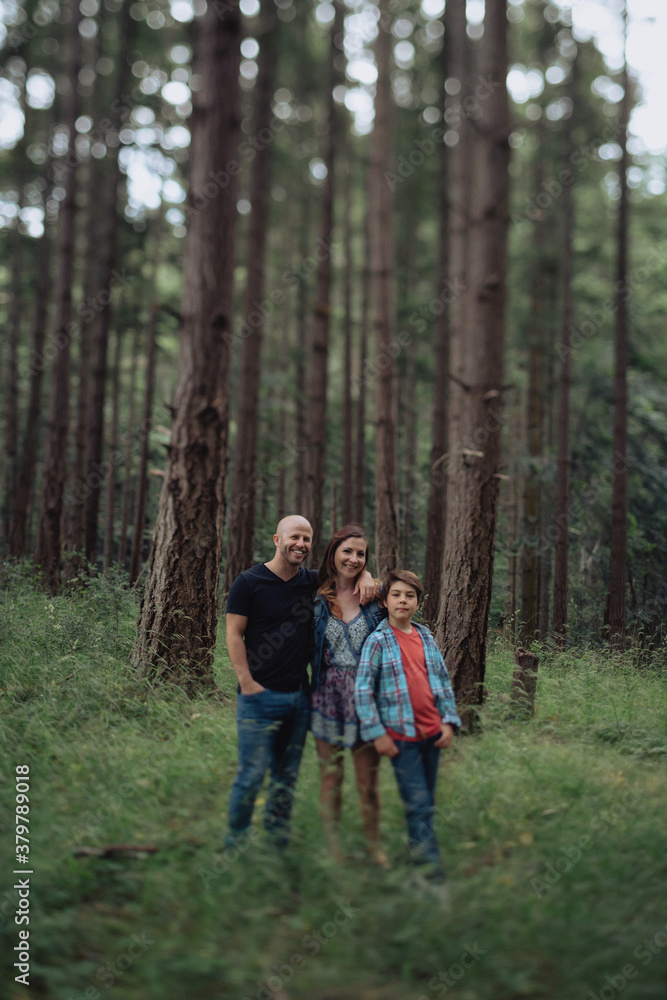 Happy family of three looking at camera together outside in nature Happy family of three looking at camera together outside in nature