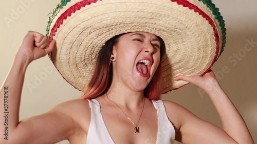 Joven mujer mexicana gritando emocionada por dia de la independencia de mexico viva con sombrero photo