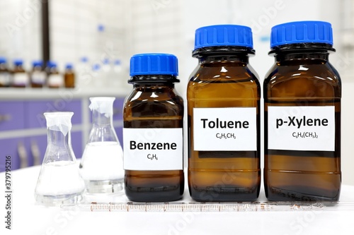 Selective focus of benzene, toluene and xylene liquid chemical compound in glass amber bottle inside a chemistry laboratory with copy space. BTX aromatic hydrocarbons used in petrochemical industry. photo