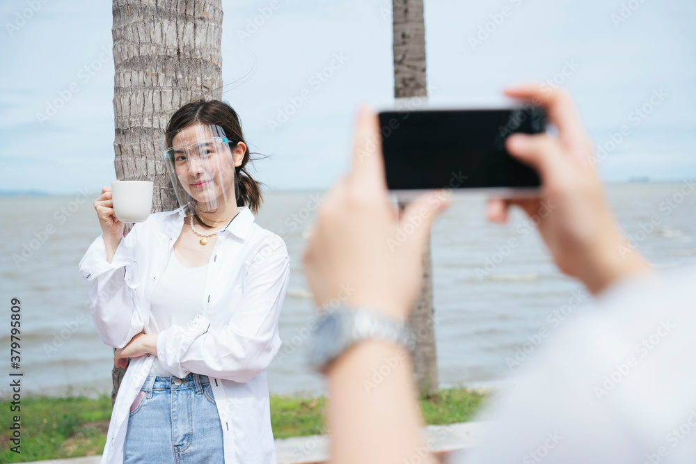 Man taking photo of his girlfriend with smartphone at the beach.