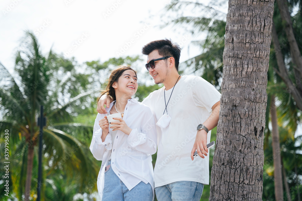 Couple traveler holding shoulder standing on the beach near coconut tree. Couple traveler holding shoulder standing on the beach near coconut tree.