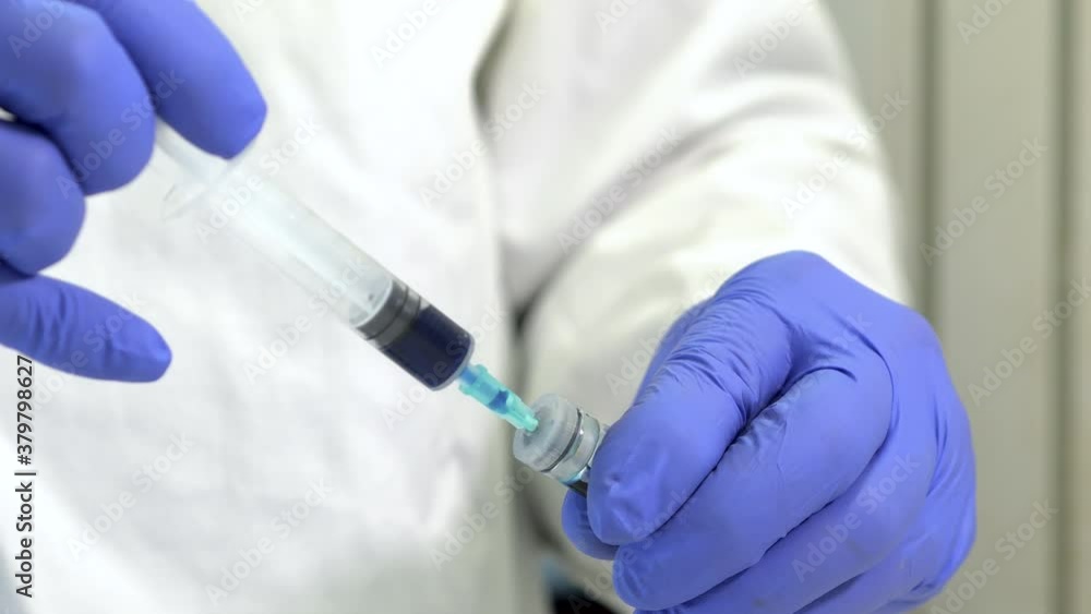 Scientific using a syringe in a laboratory. Selective focus Scientific using a syringe in a laboratory. Selective focus