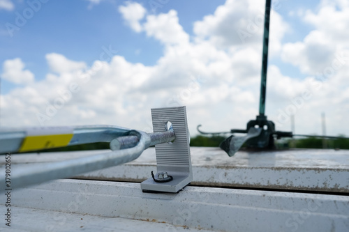 Fotografie steel cable connect with lightning rod on rooftop above metal sheet in cloudy bl