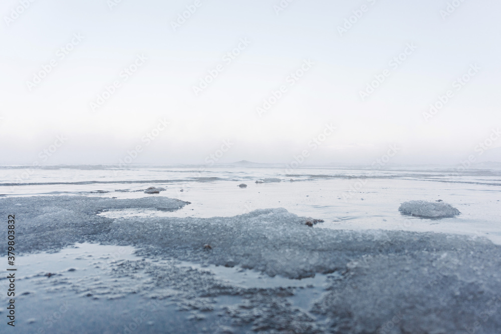 the water freezes and covers the sand with ice and snow on the seashore during the winter frost the water freezes and covers the sand with ice and snow on the seashore during the winter frost