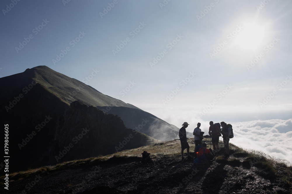 Group of hikers taking a break and enjoying the view of the scenic seacloud Group of hikers taking a break and enjoying the view of the scenic seacloud