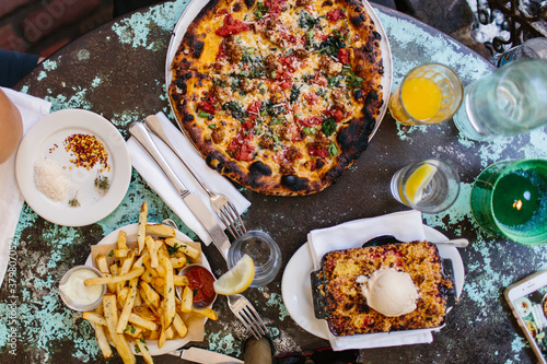 From above shot of pizza, fries and pie. Brunch food on a rustic table. photo