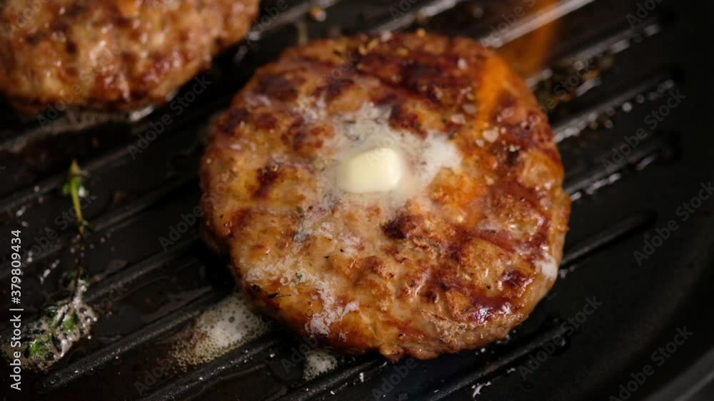 Grilled hamburgers on the grill. Burger cutlet is cooked in a grill pan, thyme, steam, smoke, fire. Butter is melted. Grill food. Slow motion. Grilled hamburgers on the grill. Burger cutlet is cooked in a grill pan, thyme, steam, smoke, fire. Butter is melted. Grill food. Slow motion.