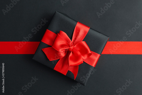 Gift box and red ribbon on black background