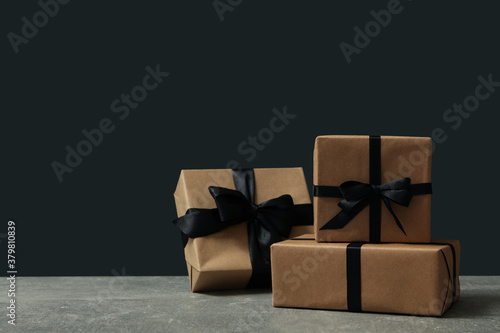 Craft gift boxes with bow on gray table against black background
