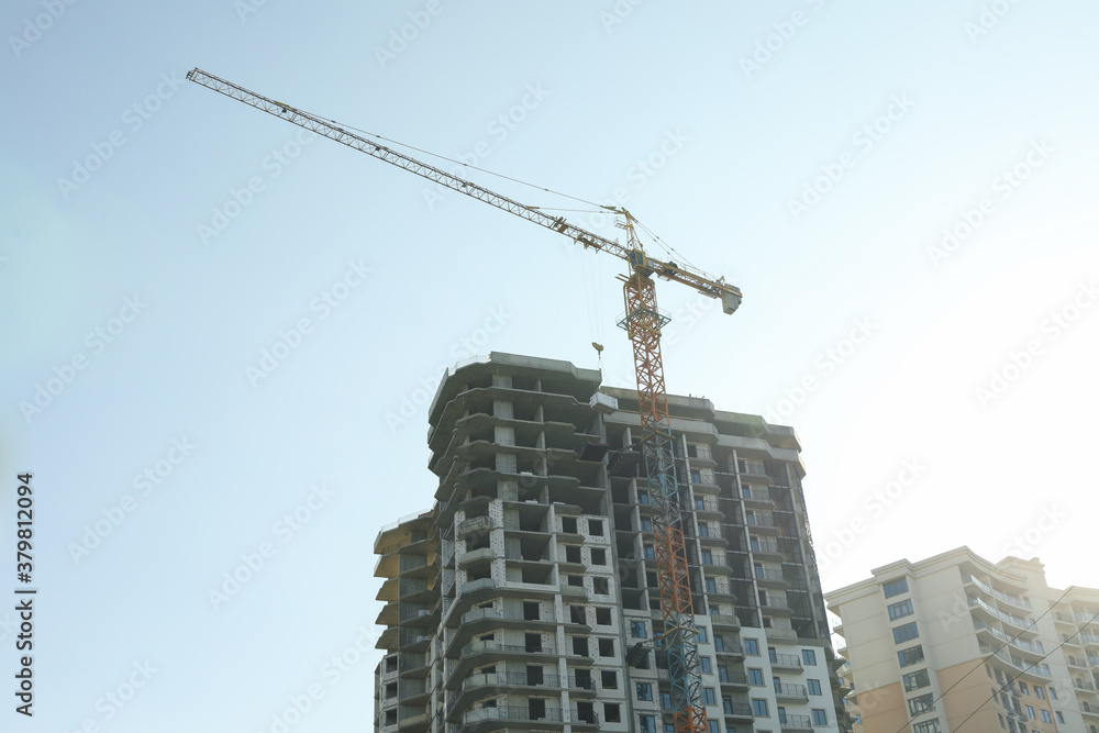 High-rise construction with crane against blue sky