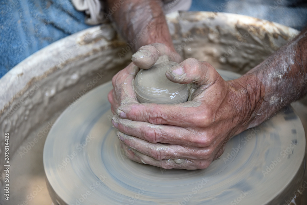 Master potter using a potter's wheel creates a vase from clay