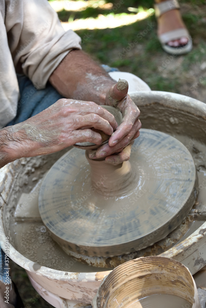 Master potter using a potter's wheel creates a vase from clay