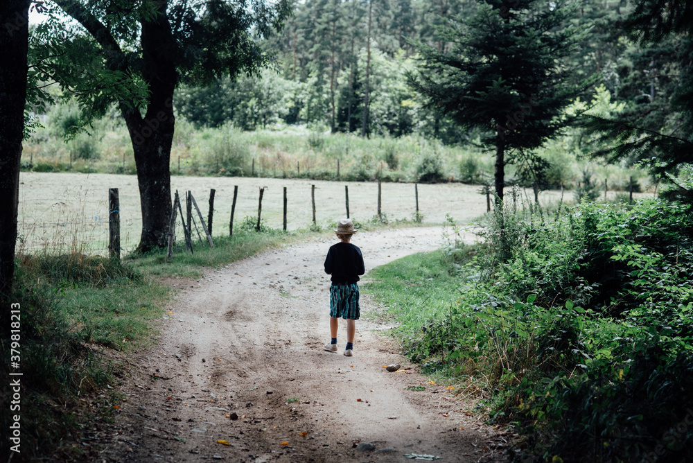 little boy with hat walking on path little boy with hat walking on path