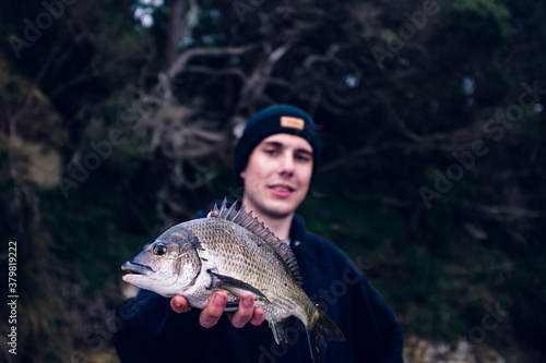 Young man holding a southern black bream (Acanthopagrus butcheri photo