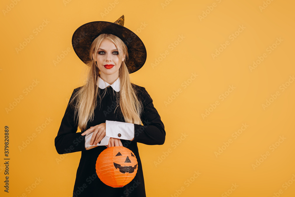Cute halloween girl holding a painted orange lettering on an orange wall background Cute halloween girl holding a painted orange lettering on an orange wall background