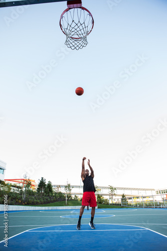 African American man shooting a basketball on an outdoor court photo