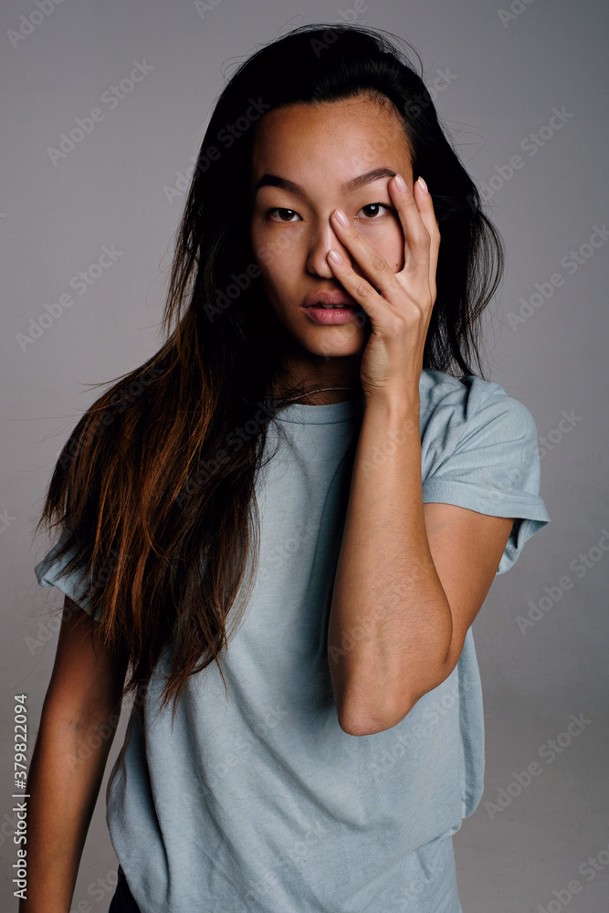 Studio portrait of long-haired Asian woman with hand on cheek Studio portrait of long-haired Asian woman with hand on cheek