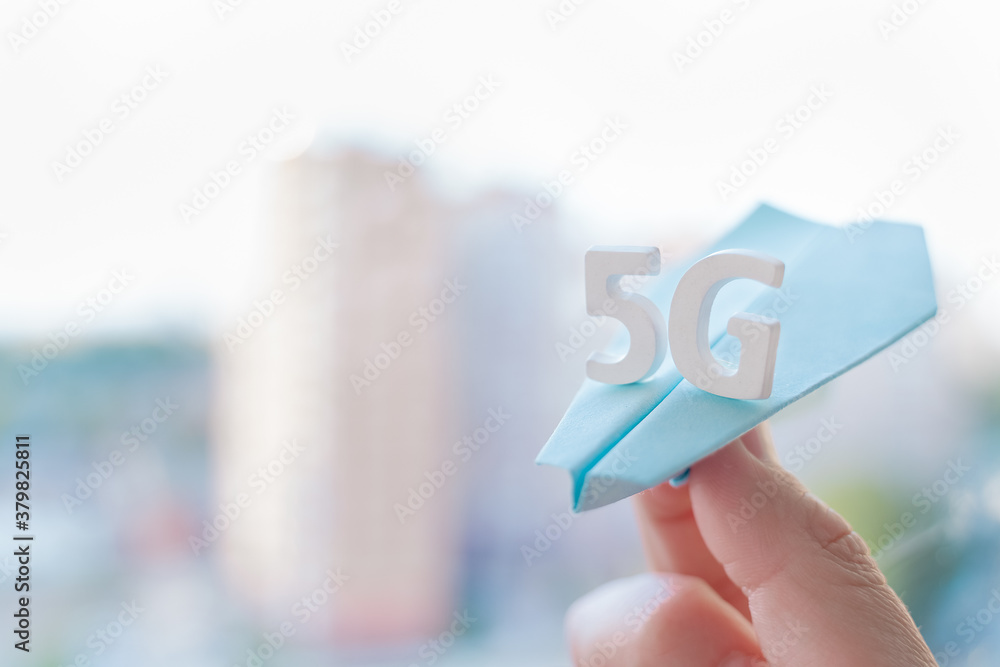 Flying paper plane with large white letters 5 G on window, city background. Creative concept. Modern wireless high speed mobile internet.Connection technology for cell, laptop,phone.Use at home, work Flying paper plane with large white letters 5 G on window, city background. Creative concept. Modern wireless high speed mobile internet.Connection technology for cell, laptop,phone.Use at home, work