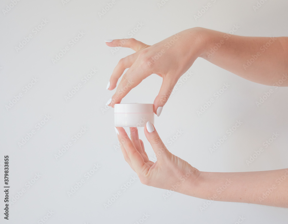 Plastic jar of cream in a female hand isolated on white. Professional cosmetics to restore skin youth, anti-aging cream. Skin care concept. Jar mockup. Plastic jar of cream in a female hand isolated on white. Professional cosmetics to restore skin youth, anti-aging cream. Skin care concept. Jar mockup.