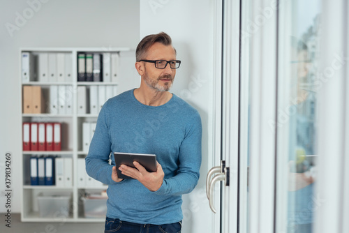 Distracted businessman peering out of a glass door
