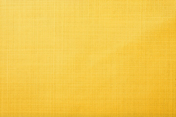 Yellow silk fabric texture background with fine weave pattern and golden glow