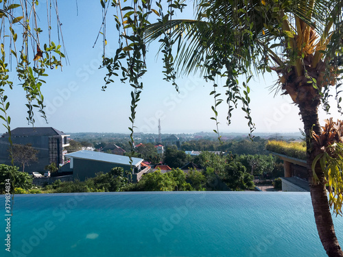 Windows views of a infinite pool and city from inside of a house