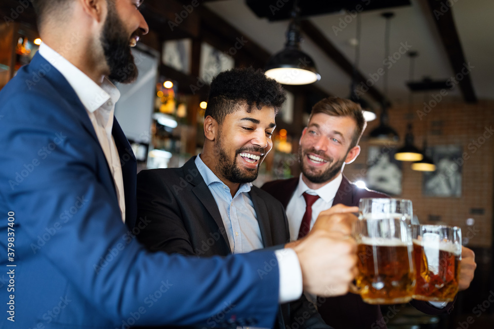 Handsome businessmen are drinking beer, talking and smiling while resting at the pub