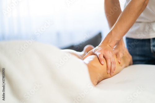 Professional masseur doing therapeutic massage. Woman enjoying massage in her home. Young woman getting relaxing body massage.