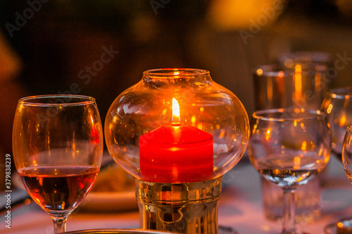 Candle stick in a glass bubble with glass of wine on the side