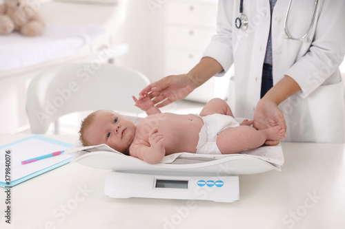 Doctor weighting cute baby in clinic  closeup. Health care