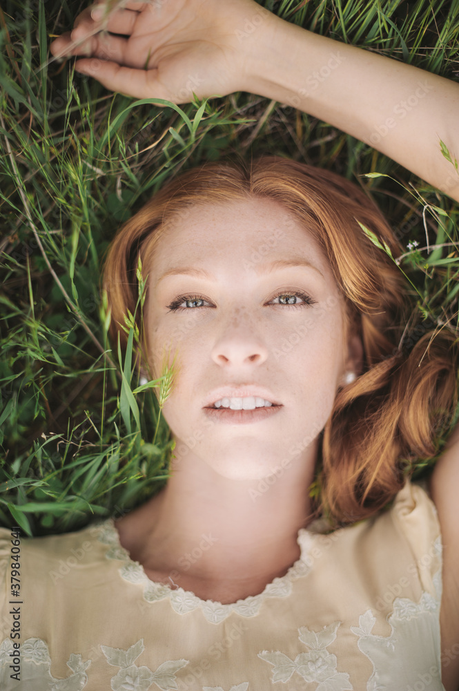 Woman with Red Hair Resting in Green Grass Field Woman with Red Hair Resting in Green Grass Field