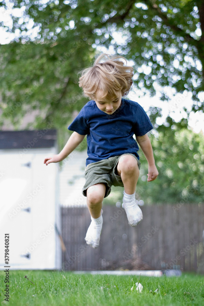Child wearing socks and no shoes jumps around in his backyard Child wearing socks and no shoes jumps around in his backyard
