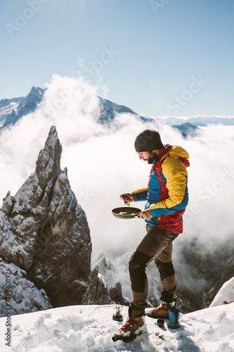 male mountaineer having breakfast - scrambled eggs - on snowcove photo