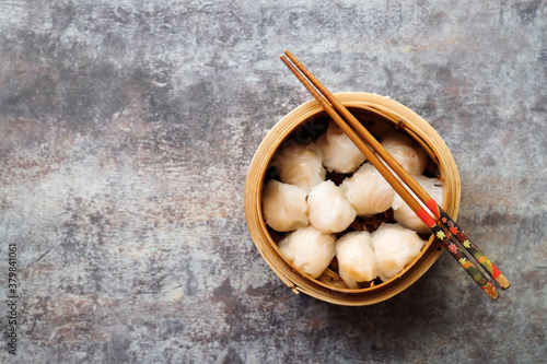 Asian steamed dish. Dim sum on a food shelves, various Chinese steamed dumpling in bamboo basket steamer in Chinese restaurants. with a chopstick