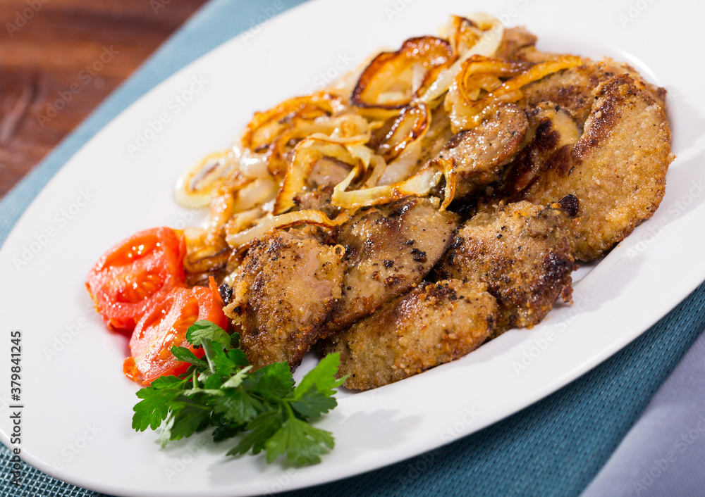 Tasty rabbit liver fried with onion garnished with fresh parsley and blanched cherry tomatoes Tasty rabbit liver fried with onion garnished with fresh parsley and blanched cherry tomatoes