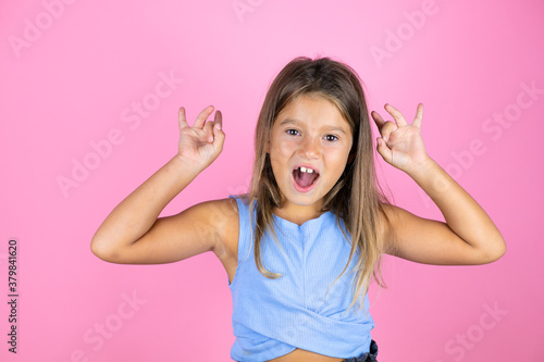 Young beautiful child girl over isolated pink background doing ok sign with fingers and smiling, excellent symbol