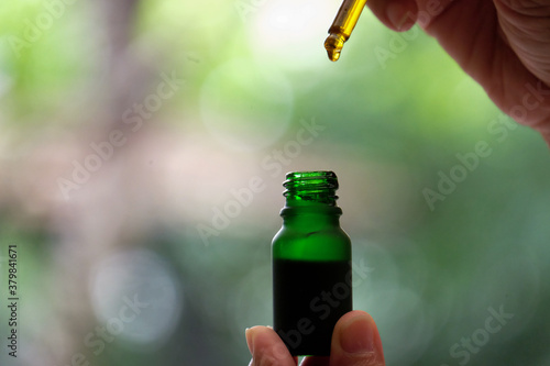 Drip hemp oil into a glass bottle.
Dropping an essential oil in the bottle. CBD oil. Cannabis. Scientific research. Medical education and research.