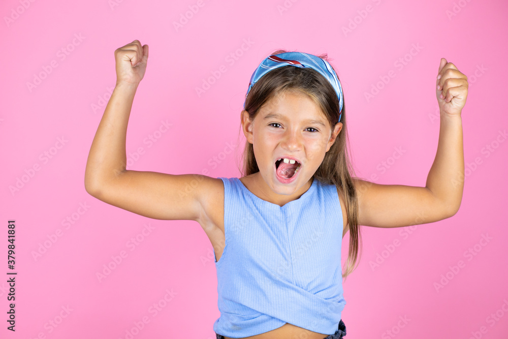 Young beautiful child girl over isolated pink background showing arms muscles smiling proud Young beautiful child girl over isolated pink background showing arms muscles smiling proud
