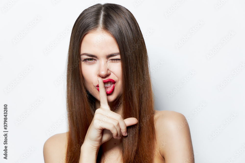 Brunette holds her finger near her lips and winks Brunette holds her finger near her lips and winks