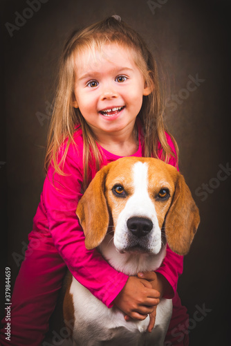 2 yeras old child hugging best friend dog. Happy childhood with pet Beagle. Dog background photo