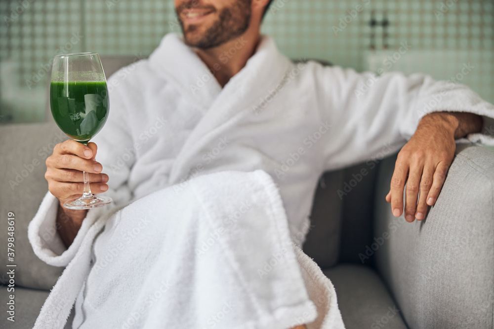 Bearded young man drinking smoothie in spa salon Bearded young man drinking smoothie in spa salon