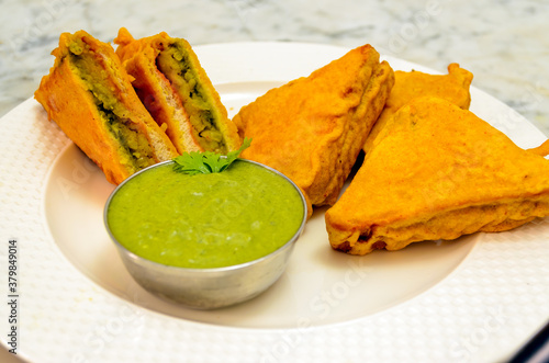 Delicious Bread Pakoda in a round white Plate along with Green Coriander Chutney