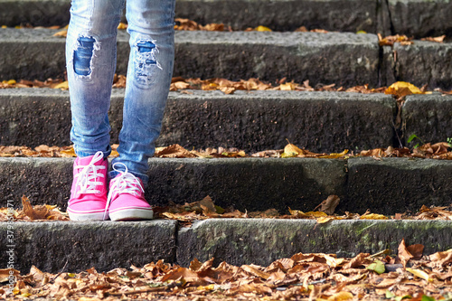 Woman in pink   purple canvas vintage shoes and blue jeans.