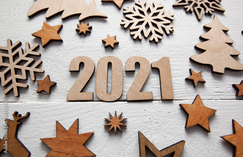 The beautiful christmas background with a lot of small wooden decorations and wooden numbers 2021 on the wooden desk.