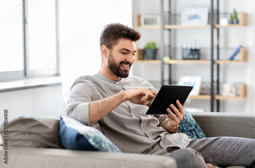 technology, people and lifestyle concept - happy man with tablet pc computer at home