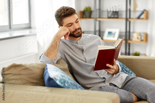 people and leisure concept - man reading book at home