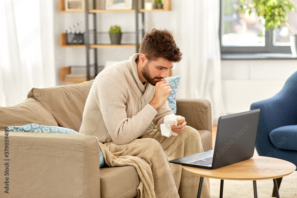 healthcare, technology and medicine concept - sick man in blanket having video call on laptop computer at home healthcare, technology and medicine concept - sick man in blanket having video call on laptop computer at home