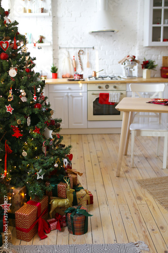 Interior of a new year's kitchen decorated with festive decor and a Christmas tree in a cozy bright house