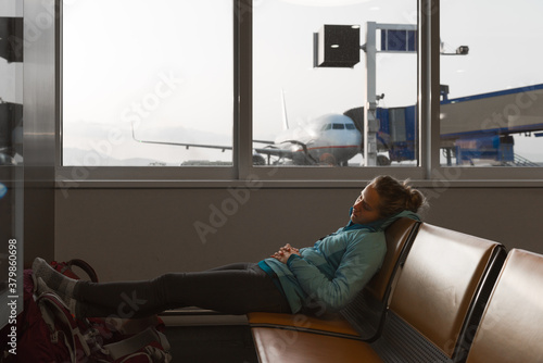 Young woman relaxing in the airport departure lounge before boar