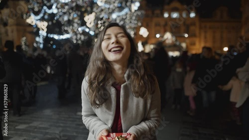 Presenting a gift to a woman at xmas night at old town square, first person view. Love, family, christmas, new year, holiday concept. Filmed on RED camera, 10 bit clolor photo